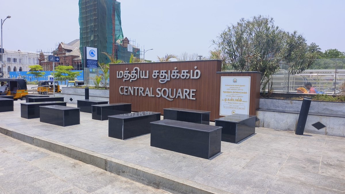 Central Square ghosted. Pedestrians walk past the seats. @cmrlofficial, lovely seating space in granite on a busy road like EVR Periyar Salai. But what is the point? Granite gets heated up in the sun, especially with no shade. Needs: Umbrellas, trees, a free water dispenser,