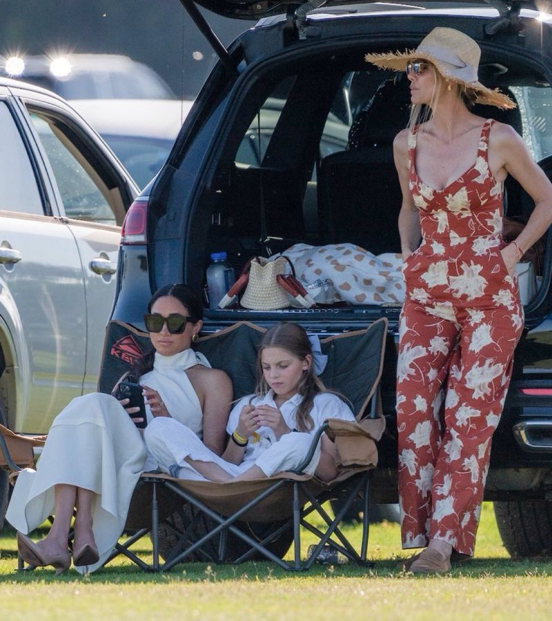 There's barely a photograph from the Sentebale Polo Challenge day that wouldn't make it to a fashion magazine spread: here's Meghan sharing a folding chair with Alba❤️checking on her kids back home in Montecito (just guessing!) looking 🔥 (as does Delfina)