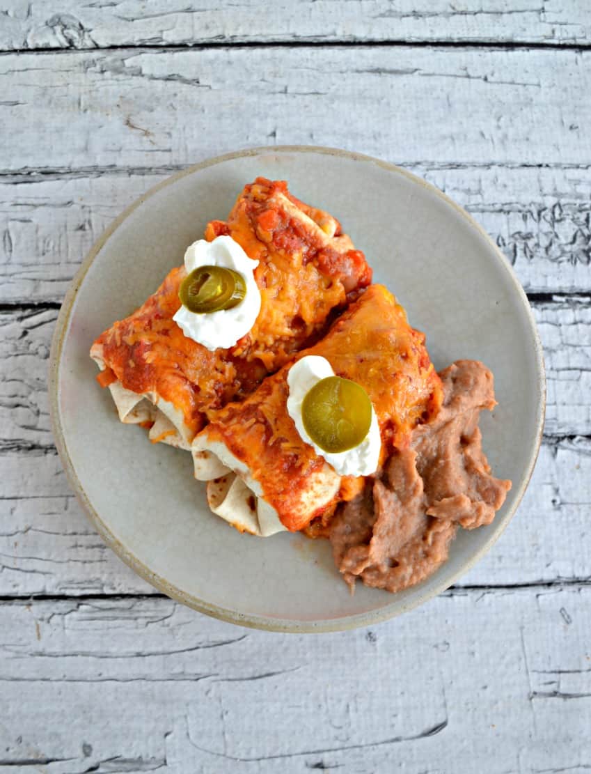 Enchiladas with Red Chili Sauce combine chicken in a mildly spicy homemade enchilada sauce rolled in tortillas then topped with sour cream and cheese for an awesome Mexican meal. #enchiladas #mexican #cincodemayo #chilisauce hezzi-dsbooksandcooks.com/enchiladas-wit…