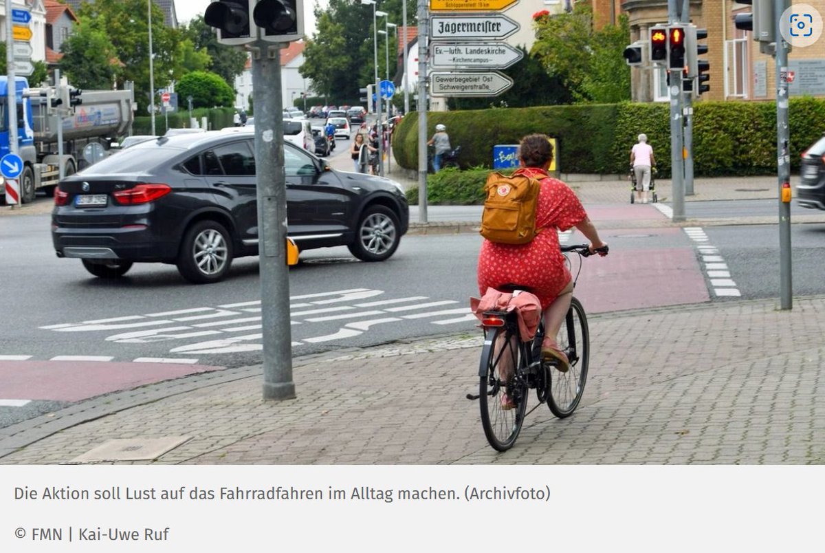 Von Text-Bild-Schere spricht man, wenn Text und Bild nicht zusammenpassen. 'Die Aktion soll Lust auf das Fahrradfahren im Alltag machen'. Dazu das Bild einer Radfahrerin auf einem miserablen Radweg vor einer Roten Ampel und einer großen Kreuzung mit Laster und SUV.