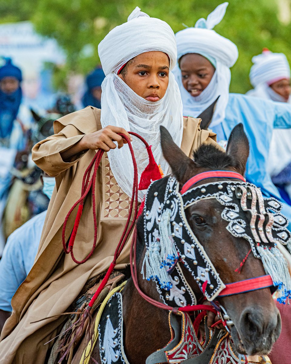 A young boy showcasing the beauty of the Hausa culture as he elegantly sat on his brown-royal horse during the Durbar Festival in Kano. Kano, Nigeria.