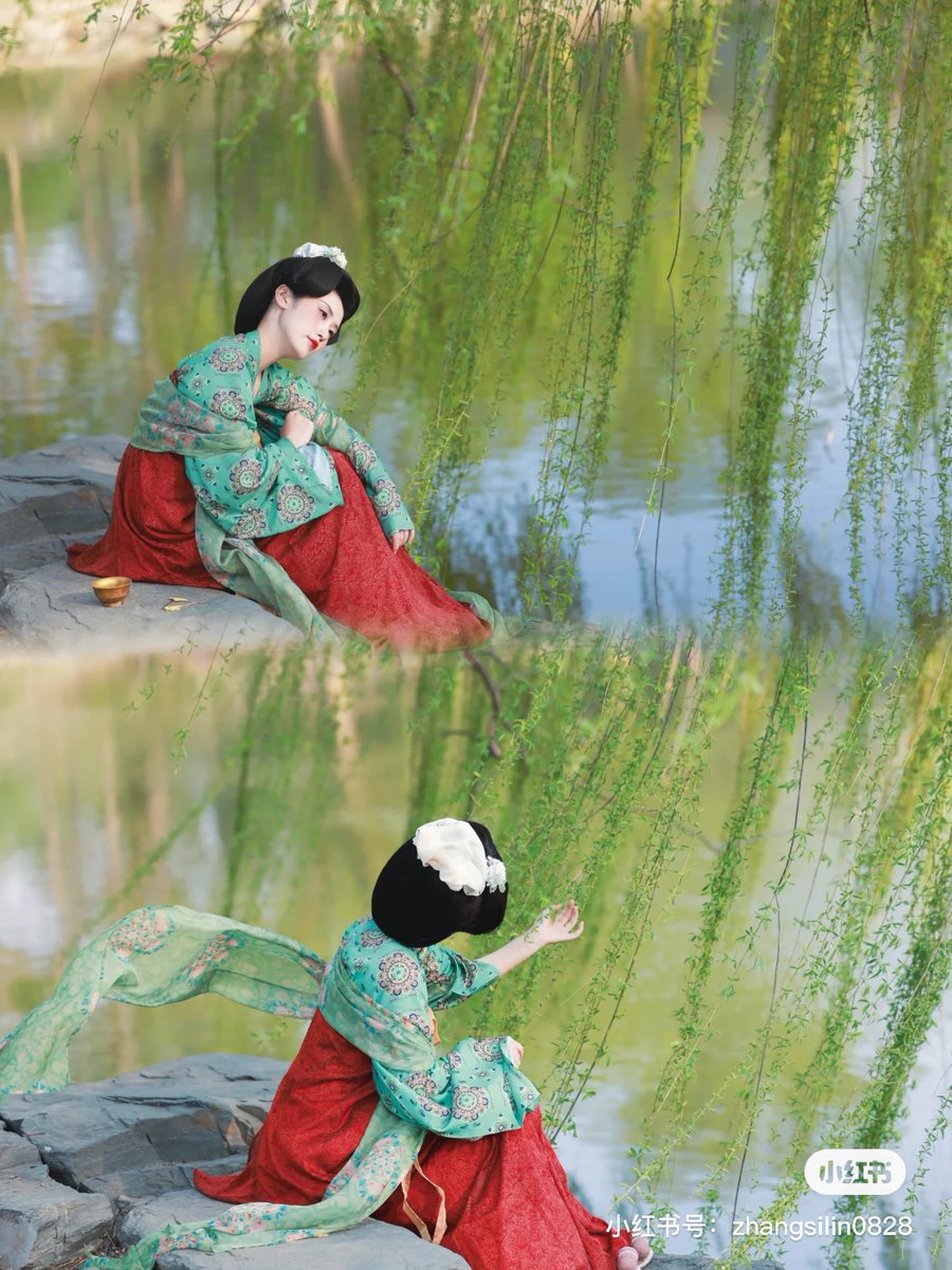 Beside a small lake in the #Yuanmingyuan Ruins Park, a girl dresses in a red #TangDynasty-style Ruqun while pairing it with a green embroidered blouse. She enjoys the beautiful #spring scenery under the swaying willow branches. (Via: Shixiaolinwa) #Hanfu