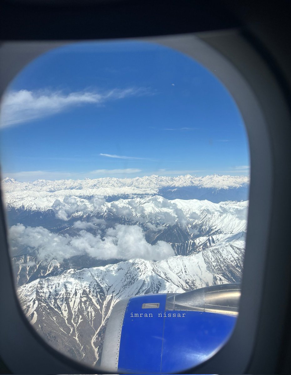 Peering through the window, Kashmir's majestic snow-capped peaks paint a breathtaking panorama.