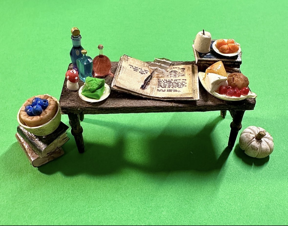 A little hand-made table for Bilbo Baggins ft sculpted lembas bread, cheese plates, tarts, candles, quill from a real feather, and pages from There and Back Again 🍃✨