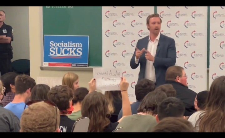 Having this sign proudly displayed while speaking at a state university while being guarded by a tax payer funded police officer while taxpayers fund your office, career and your self promotion campaign to land a job in the next administration is the apex of idoicracy.