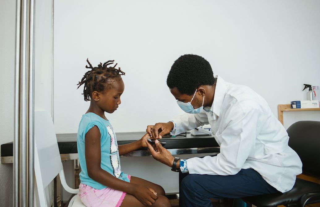 Elisa, an 8-year-old with type 1 diabetes, finds comfort in toys & games while waiting for her appointment at Nhamatanda District Hospital, a #PENPlus-implementing facility in 🇲🇿. Inside, Dr Lindolfo monitors her blood sugar, ensuring a calm environment for effective management.
