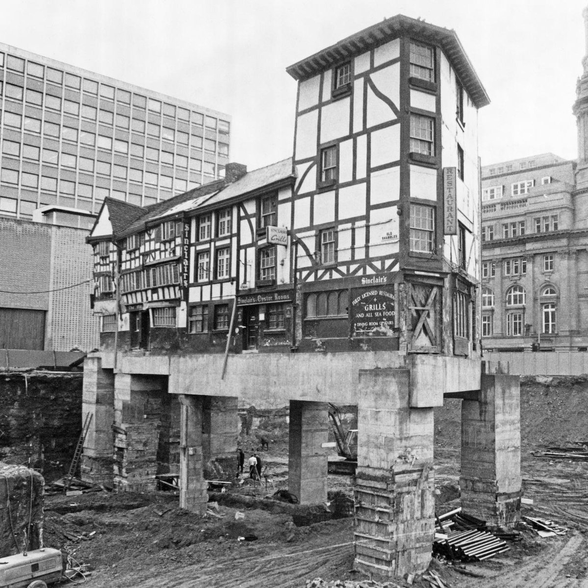The Old Wellington Inn and Sinclair’s Oyster Room in Manchester were once a house, built around the mid-16th century. This photograph was taken in 1971 when the building was underpinned and raised to fit the new street level. It was later moved as Shambles Square was developed.