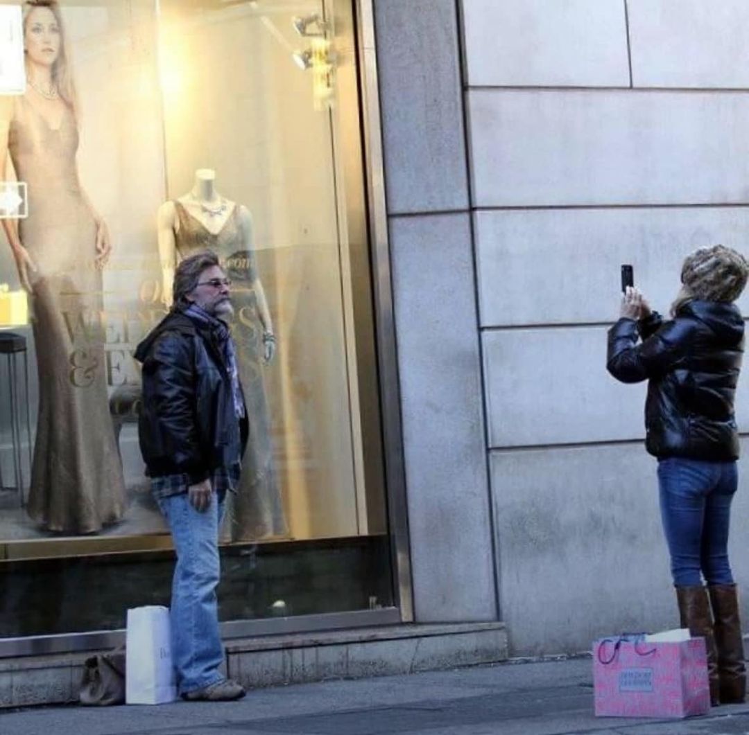 Goldie Hawn takes a photo of Kurt Russell in front of a Kate Hudson poster.