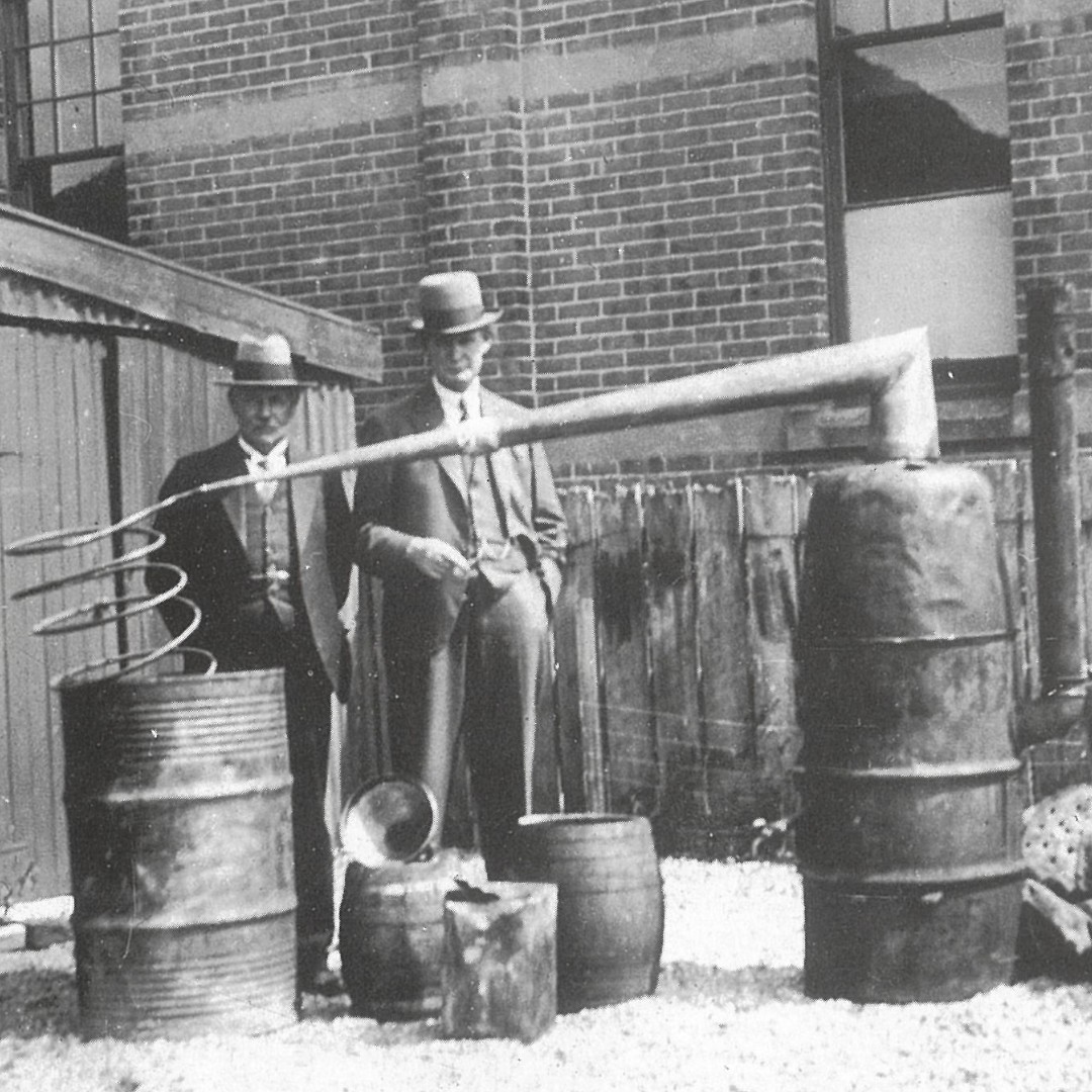 This #ThrowbackThursday was taken by the Collector of Customs Hugh Cordery, in 1933. It shows Detective Sergeant Hewitt and Inspector Fahey with seized distilling equipment and illegal distillery paraphernalia, near Gore.