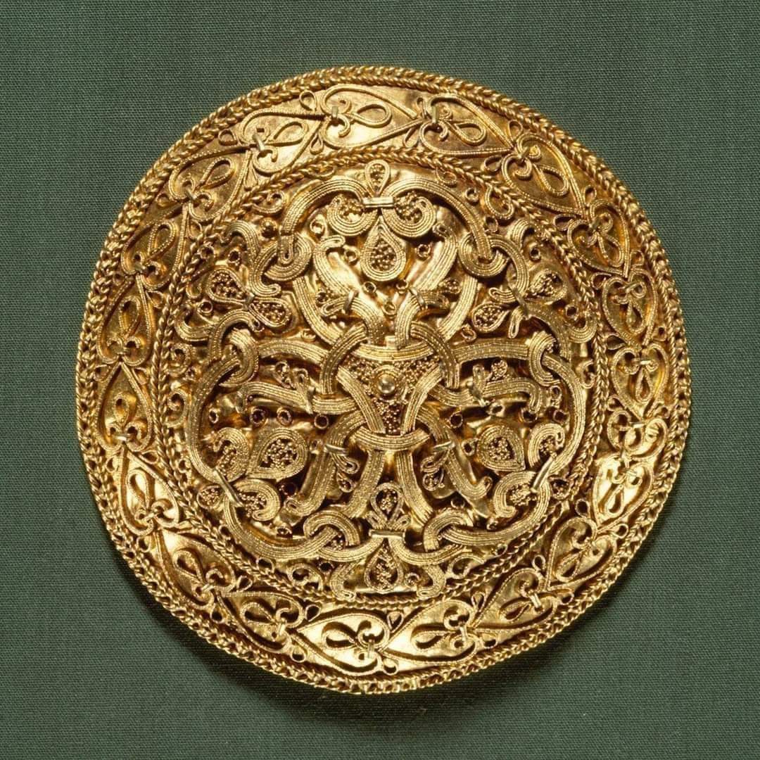 This stunning Viking brooch, created in Denmark around a thousand years ago, showcases impeccable craftsmanship and intricate design. Made from gold, it features elaborate granular and wire filigree decorations, demonstrating the skill of a highly talented artisan. The level of