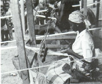 Weaver at Oke-Apena, Ibadan, Nigeria, 1990. 
The young woman, like the other male weavers at work, is weaving an openwork pattern within a mixed cotton and lurex warp. (Photograph by John Picton)

History, Design and Craft in West African Strip-Woven Cloth