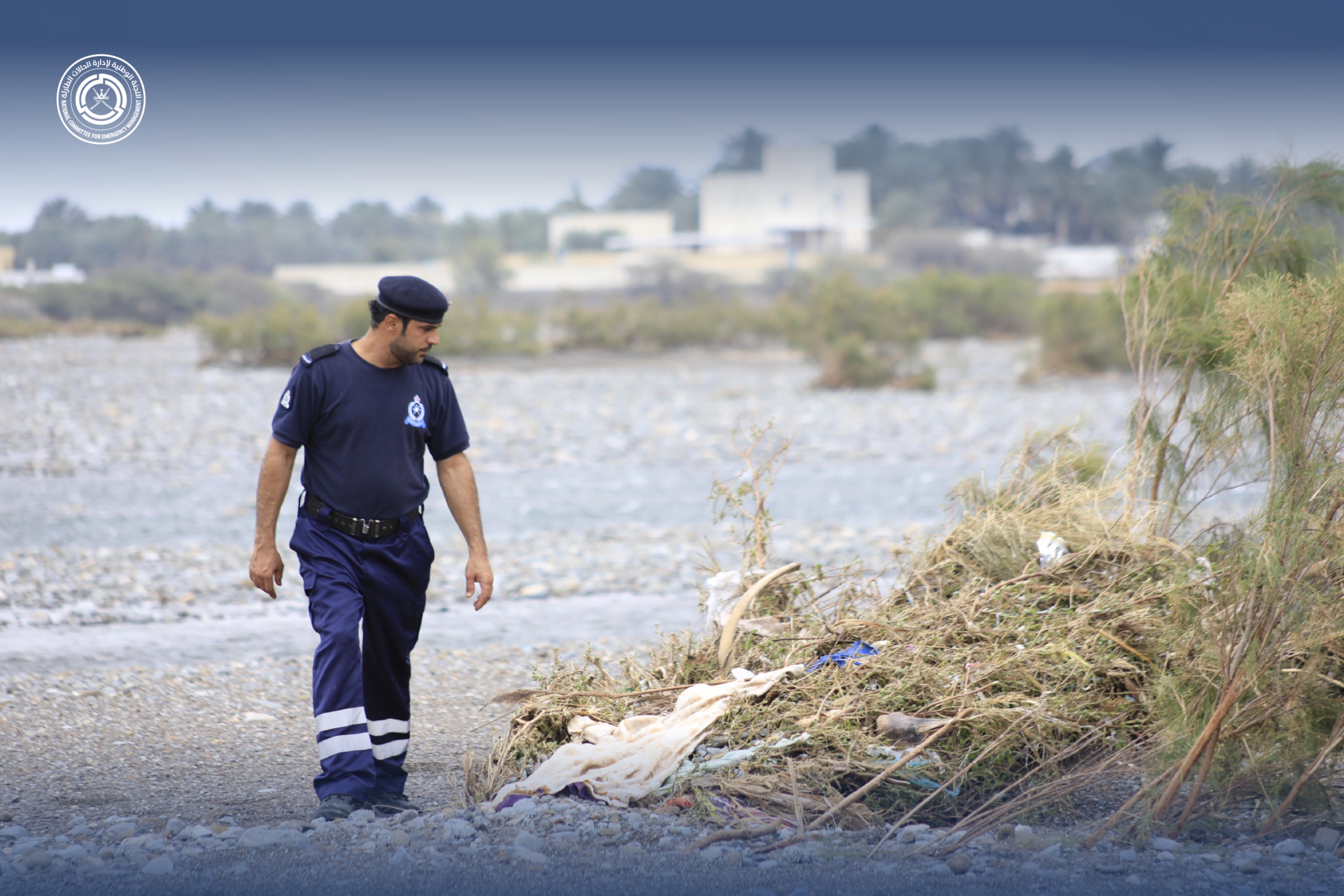 فرد من أفراد شرطة عمان السلطانية في احدى الأودية وهو يشوح بنظره إلى مجموعة مخلفات متكدسة مع بعضها البعض بحثا عن المفقودين