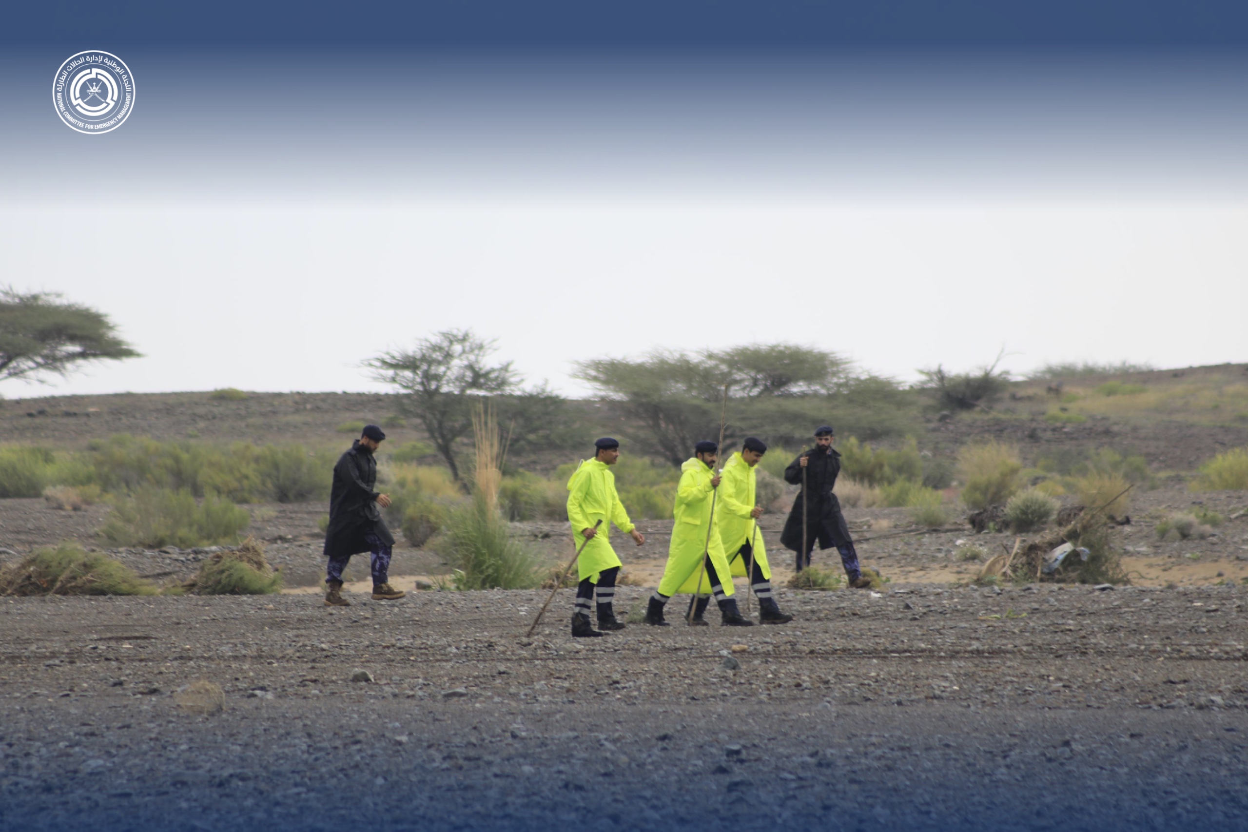 خمسة أفراد من شرطة عمان السلطانية في احدى السهول وهم يتقدمون للأمام بحثا عن المفقودين 