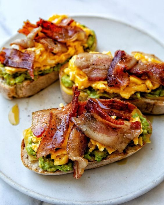 Avocado, Bacon And Egg Toasts Sourdough toast topped with mashed avo, soft scrambled eggs, bacon, and hot honey