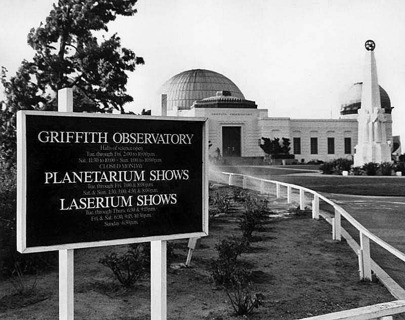 [undated] Exterior view of the Griffith Observatory.  In the foreground is a sign giving hours for the Observatory and for the Planetarium and Laserium shows. (Tom LaBonge Collection) buff.ly/3U3w1bx