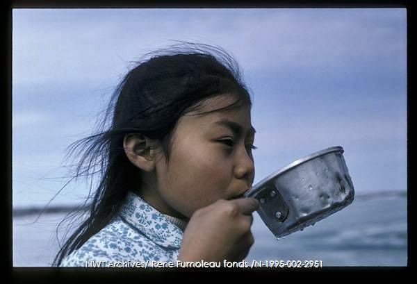 Bessie Martin (Yellowknives Dene) using a dipper to enjoy some fresh water. Photographed near Dettah, Northwest Territories in 1970. 📷 Rene Fumoleau | NWT Archives
