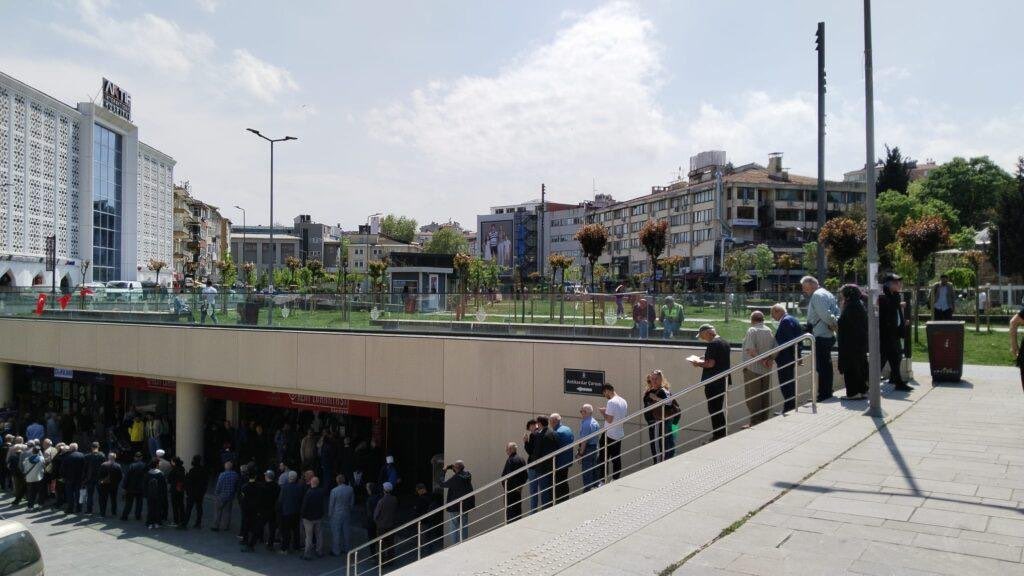tcbuyuksehIr1's tweet photo. Gazeteci Buse Çelebi, İBB Üsküdar Kent Lokantası'ndan gözlemlerini aktardı:

"Sıradaki insanlar Çapa'daki lokanta açılırken hedeflenen öğrenci kitlesinden çok farklı. Genellikle 55 yaş üstü ve emekliler. İçeriden çıkanlara yemekleri soruyorlar, herkes birbirini çok önceden tanıyormuş gibi davranıyor ama aslında tanışmadıklarını sohbetlerinden anlıyorum.

Sırada emekli Fuat Bey'le tanışıyorum. Fuat Bey ilk defa geliyor, iki çocuk büyütmüş, iki de ev almış onlara zamanında. O bunları anlatırken önümüzdeki emekli Kenan Bey sohbete dahil oluyor, 'Ben ikinci kez geliyorum, yemekleri hem güzel hem de ucuz. Bu yemeği dışarıda yesem her gün 300-400 TL öderim. Nasıl ödeyeyim?'

Arkamızdaki koyu Fenerbahçeli olduğunu yeleğinden anladığımız Ali Bey 'Buranın esas sırrı hijyende. Tertemiz içerisi ve yemek yedikten sonra midem ağrımıyor. Kullandıkları yağlar kaliteli demek ki' diyerek sohbete dahil oluyor. Ali Bey İstanbullu, ailesi 95 yıldır Kasımpaşa'da yaşıyormuş.

Sıranın sonundan lokantanın kapısına gelmek 45 dakika sürüyor. Kapıdan girdik, görünen 3 kadın çalışan var. Biri fiş veriyor, diğer ikisi büfede yemek dağıtıyor. Güler yüzlüler ve o yoğunluğa rağmen çalışmakta istekliler.

Herkes oturduğu masada birbiriyle tanışıyor ama muhabbetin karşısındakini sıkıp sıkmadığına dikkat ederek konuşuyor.

Karşıma yaşlı bir kadın geliyor. Torunu 'arkadaşlarım gelecek' deyince dışarı çıkmış, buraya gelmiş. 'Ben nasıl dışarıda yemek yiyebilirim ki, fiyatlar ortada ama AKP istemedi burayı' diyor.

Masalar yiyemediklerini birbirine ikram ediyor. En çok edilen turşu, çünkü tuzlu.

Biz yemeğimizi yerken içeri hurdacılık yapan biri giriyor, üstü kirli olduğu için yemeği alıp çıkmak istiyor ama dışarı yemek verilmiyor. Hurdacıya yanıt olumsuz olunca, o da çıkmak istiyor. Ama yemek dağıtan kadınlardan biri cevval, hemen atılıyor:

-Hayır, çıkma otur. Burada ye.

-Yok benden rahatsız olurlar.

-Niye rahatsız olsunlar, sen vatandaş değil misin?

Hurdacı üzerine bakıyor, bir şey diyemiyor, gitmek istiyor. Kadın çalışan bir kez daha atılıyor, masaya dönüyor 'Beyefendi siz rahatsız olur musunuz?', yaşlı bir beyefendi 'Rica ederim, ne demek' diye yanıt veriyor. Sonunda oturmaya ikna ediyorlar ve yemeğini çalışan kadın getiriyor masasına.

Bu tartışma karşımdaki babaanneyi üzüyor, 'Rahatsız ederim diyor ya' diyerek dertleniyor ve önündeki yemeğe bakıyor."

(10Haber)