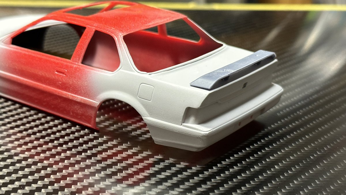f2_design's tweet photo. トランクスポイラーを追加。
こういう形の時は取り付け方法にやや悩むので、あらかじめステーを貫通させた穴付き。
仮置きして位置を決めたら上からトランクごと穴を開け、スポイラには虫ピン等を差し込んで取り付け。上面をパテ埋めして虫ピンの頭を隠せば完了の親切設計。 https://t.co/USCEWS9X6j