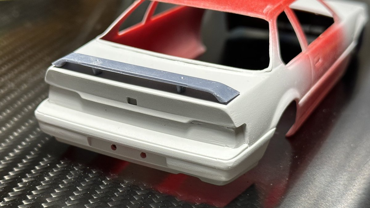 f2_design's tweet photo. トランクスポイラーを追加。
こういう形の時は取り付け方法にやや悩むので、あらかじめステーを貫通させた穴付き。
仮置きして位置を決めたら上からトランクごと穴を開け、スポイラには虫ピン等を差し込んで取り付け。上面をパテ埋めして虫ピンの頭を隠せば完了の親切設計。 https://t.co/USCEWS9X6j
