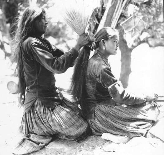 Navajo (Diné) mother tying her daughter's hair using brush. (1920s?). Source - University of Wyoming, American Heritage Center.