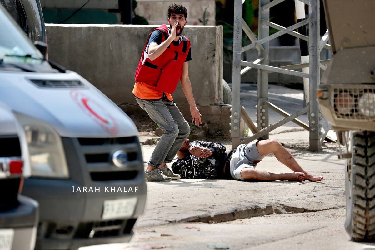 قوات الاحتلال تلقي أحد المصابين برصاصها على جانب الطريق بعد اعتقاله خلال اجتياح مستمر لمخيم نور شمس في طولكرم.