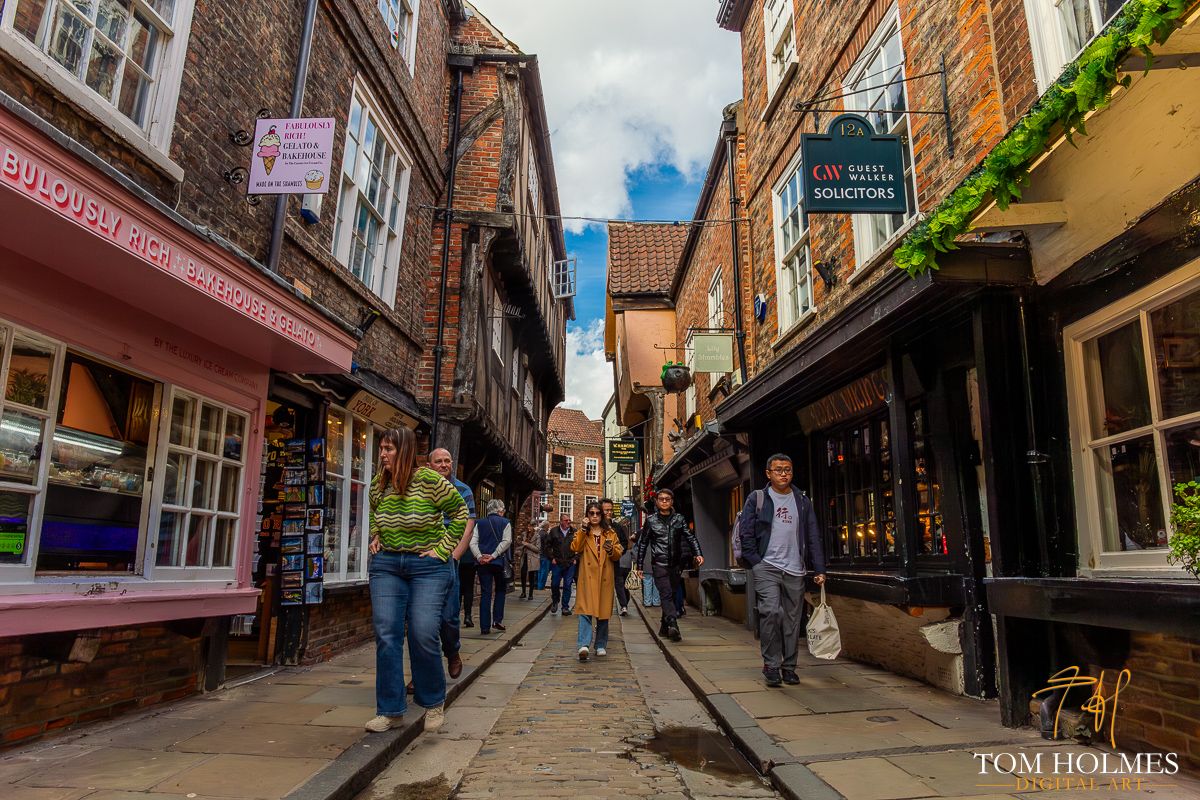 "An Amble In The Shambles"
The Shambles in York, UK is a charming and picturesque street that dates back to the medieval times. The narrow, cobbled lanes are lined with overhanging timber-framed buildings that lean towards each other, creating a tunnel-like effect.