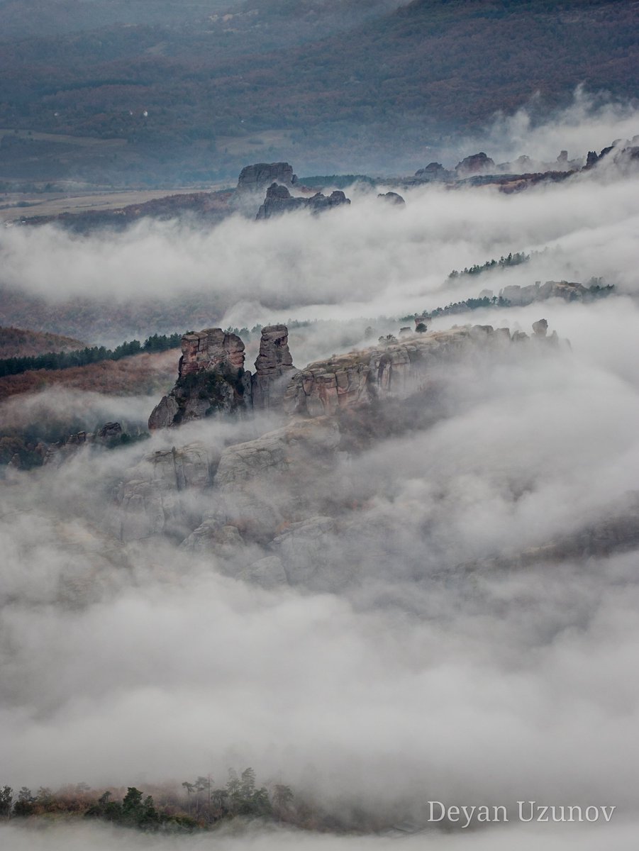 Mystical Belogradchik Rocks Enshrouded in Ethereal Mist Behold the mesmerizing Belogradchik rock, its rugged form veiled in a soft blanket of clouds and mist. From this aerial vantage, nature paints a surreal masterpiece, evoking a sense of wonder and intrigue.