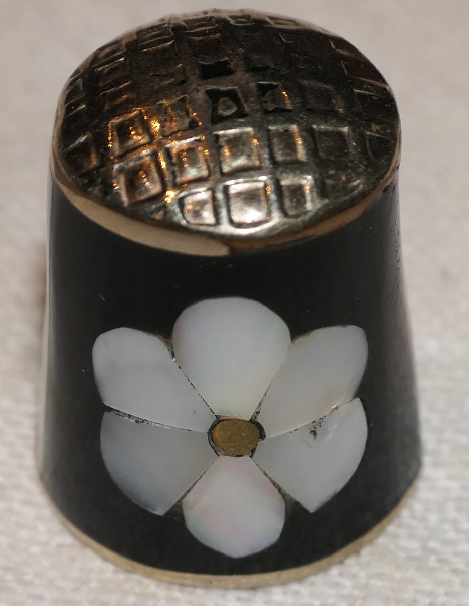 Thimble, metal, with black enamel and a mother of pearl inlaid petal.