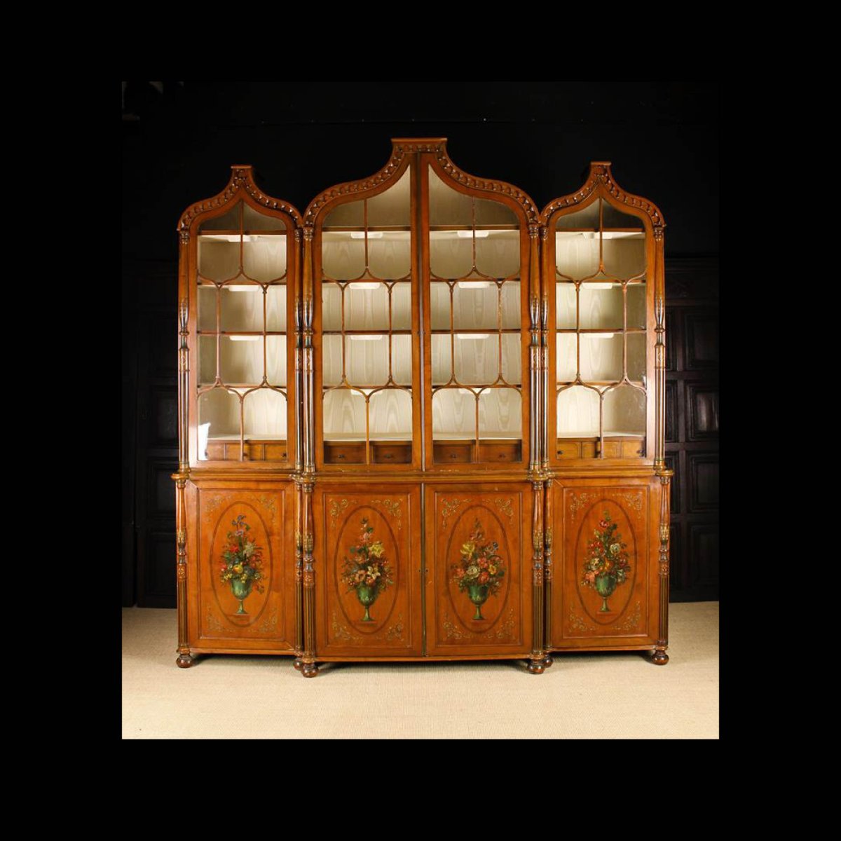 Don't miss our second sale day. A Large & Impressive Edwardian Painted Satinwood Bookcase (A/F). The upper section composed of a central glazed twin-doored cupboard flanked by single-doored side cupboards beneath ogee arched pediments adorned with decorative mouldings. Lot 676.