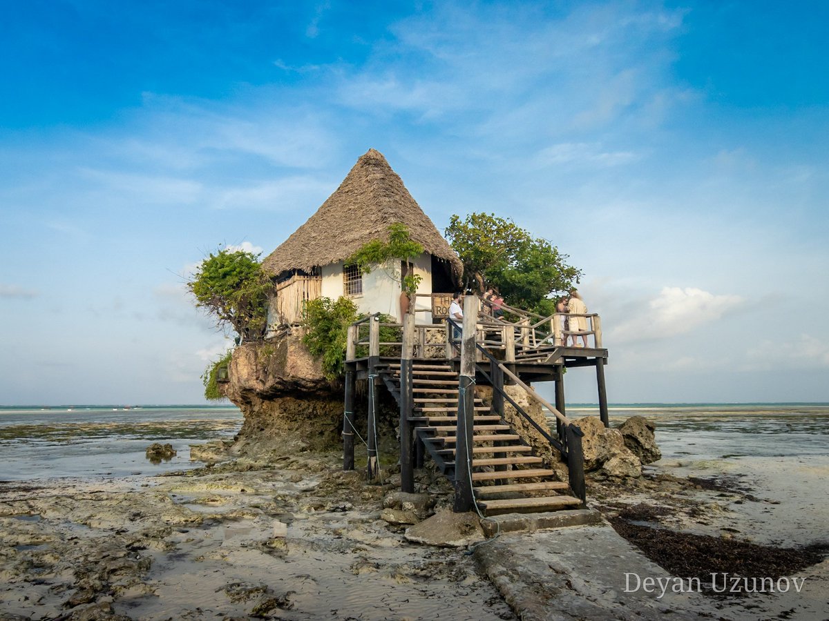 The Zanzibar Rock Restaurant at Sunset As the golden hues of sunset paint the sky, The Rock Restaurant emerges against the horizon. Nestled near Pingwe village on the enchanting Michamvi Peninsula, this iconic eatery is renowned for its 'painfully postcard-perfect' setting.