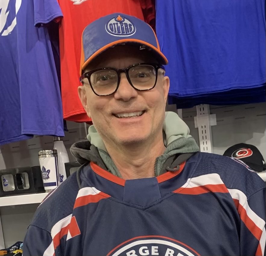A lost bet to ⁦@stevestred⁩ has found me wearing an Oilers cap in public! My smile veils my total humiliation.