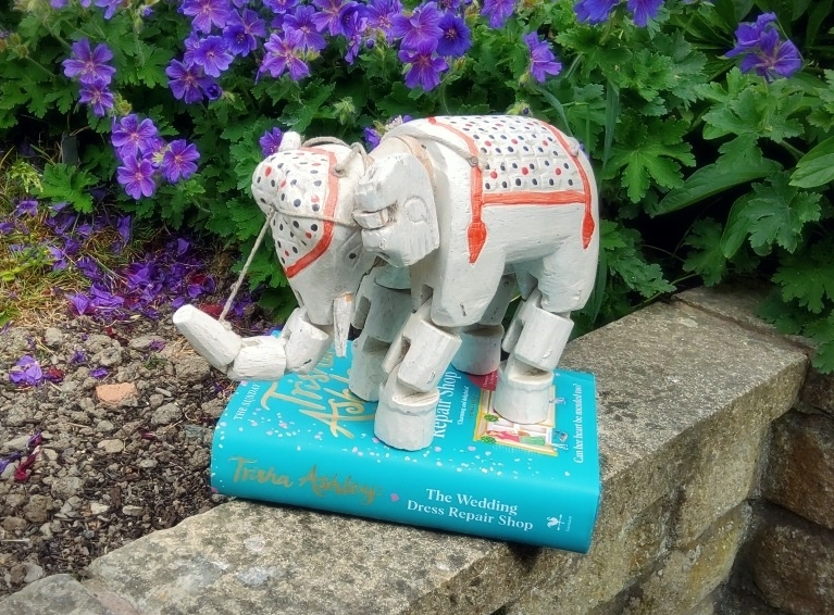 A wooden elephant puppet stands guard over the hardback of the Wedding Dress Repair shop - and now you can buy the paperback! (But not the puppet - found in a charity shop many, many years ago.)