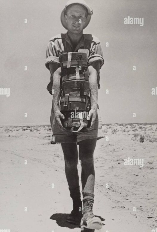 A South African with the British forces in the Western Desert holding a stack of land mines. Combat engineers place the mines