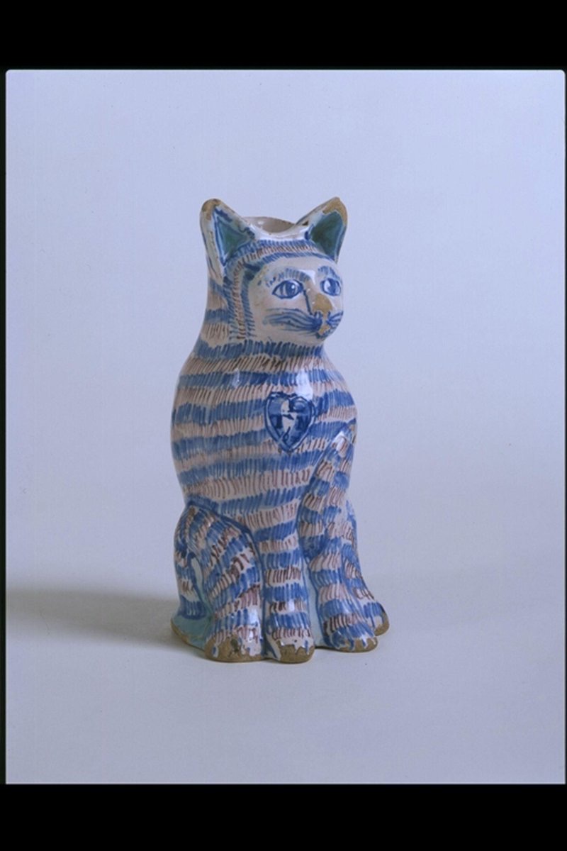 Drinking vessel in the form of a #cat with painted stripes, made of tin-glazed earthenware, London, 1676. (Victoria & Albert Museum, London)