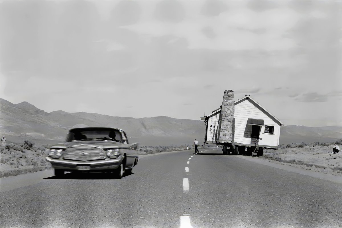 Ernst Haas - Snail’s Pace, a house being transported on a trailer along a road in Nevada - 1960