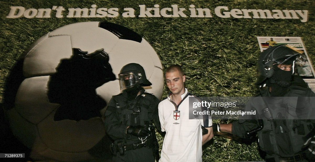 An English fan is detained under a billboard near Schlossplatz in Stuttgart, Germany. German riot police sectioned off around 200 England supporters after scuffles broke out between rival England and German fans in Stuttgart's main square (2006)