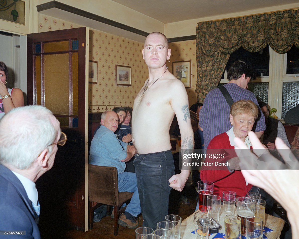 A skin head without his top on postures in a pub in the Lancashire village of Bacup. (2001)