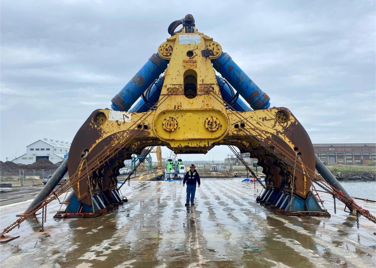 A Unified Command longshoreman stands next to a massive 200-ton hydraulic salvage grab that arrived this weekend at Sparrows Point after a weeklong barge journey from Galveston, Texas. 🏗