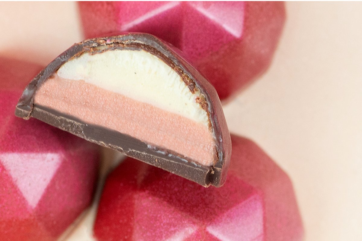The classic combination of Strawberries &amp; Cream is the inspo for our next gem. A layer of strawberry ganache topped with a layer of vanilla bean ganache, completed in a ruby shell!
