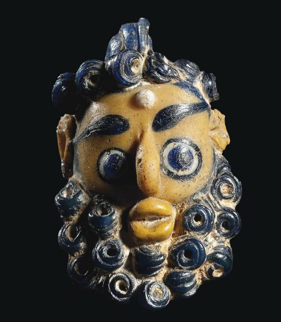 Carthaginian Glass Head Pendant, C. 5th-4th century BC. The earliest type of head-pendants date to the 6th century BC and were produced in Phoenicia. Later types such as this one were produced in the Phoenician colony of Carthage as well as other Phoenician settlements located