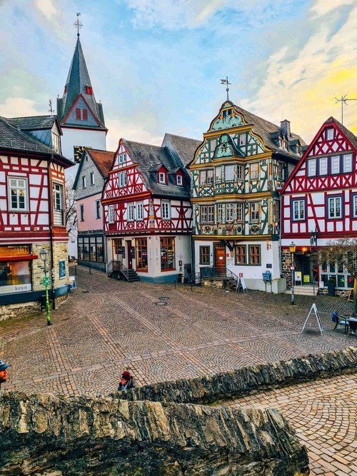 An open town square with many colorful traditional German buildings and the top of a church in the distance... @Architectolder #Germany #Architecture #Travel #Photography