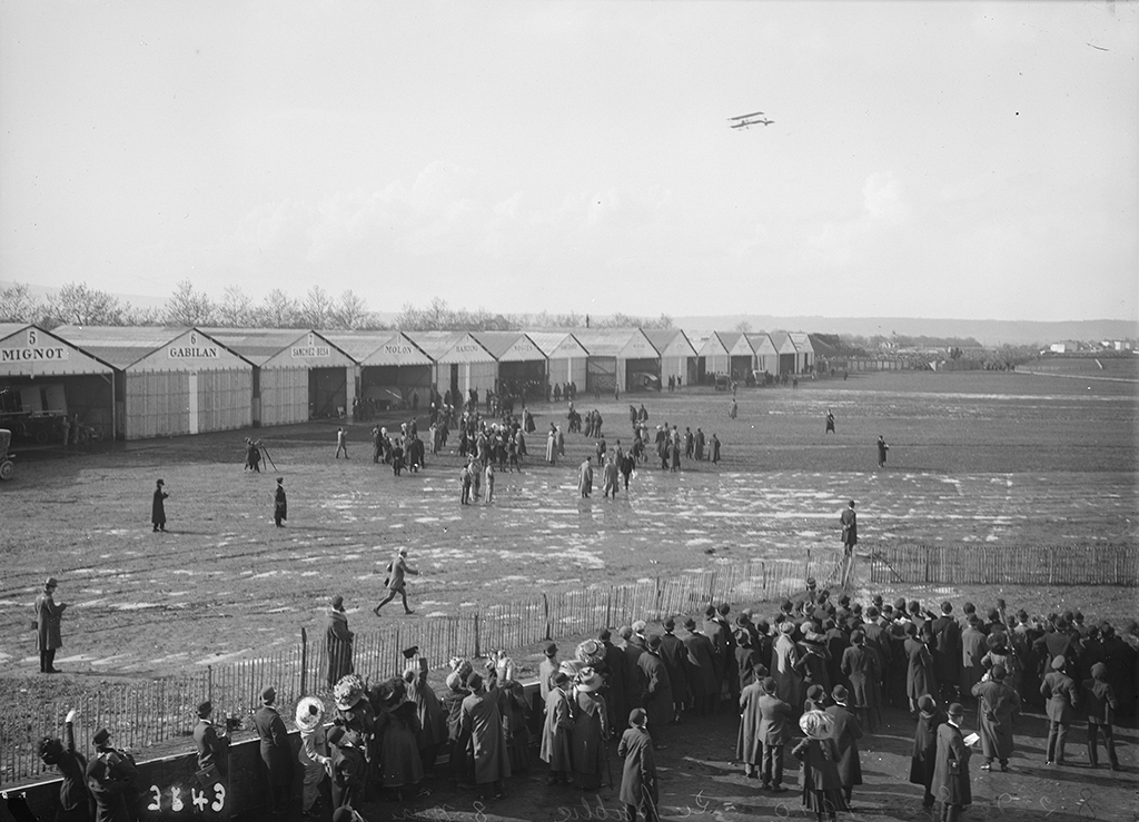 #CeJourLà #OnThisDay - Les spectateurs s'agglutinent derrière les barrières, lors du premier jour de la Semaine d'Aviation de la @villedelyon, sur le terrain de la Poudrette à Villeurbanne, le 7 mai 1910 #Avgeek