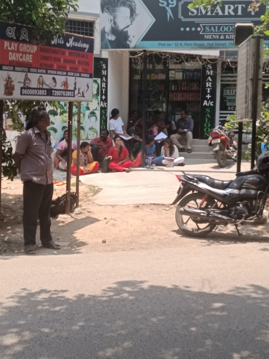 Parents wait outside a NEET exam centre in Chennai. With no alloted place to wait while their kids write NEET, parents sat on the ground in shop fronts & along roadside for shade, often using the promotional pamphlets of various coaching institutes handed out to them as mats.