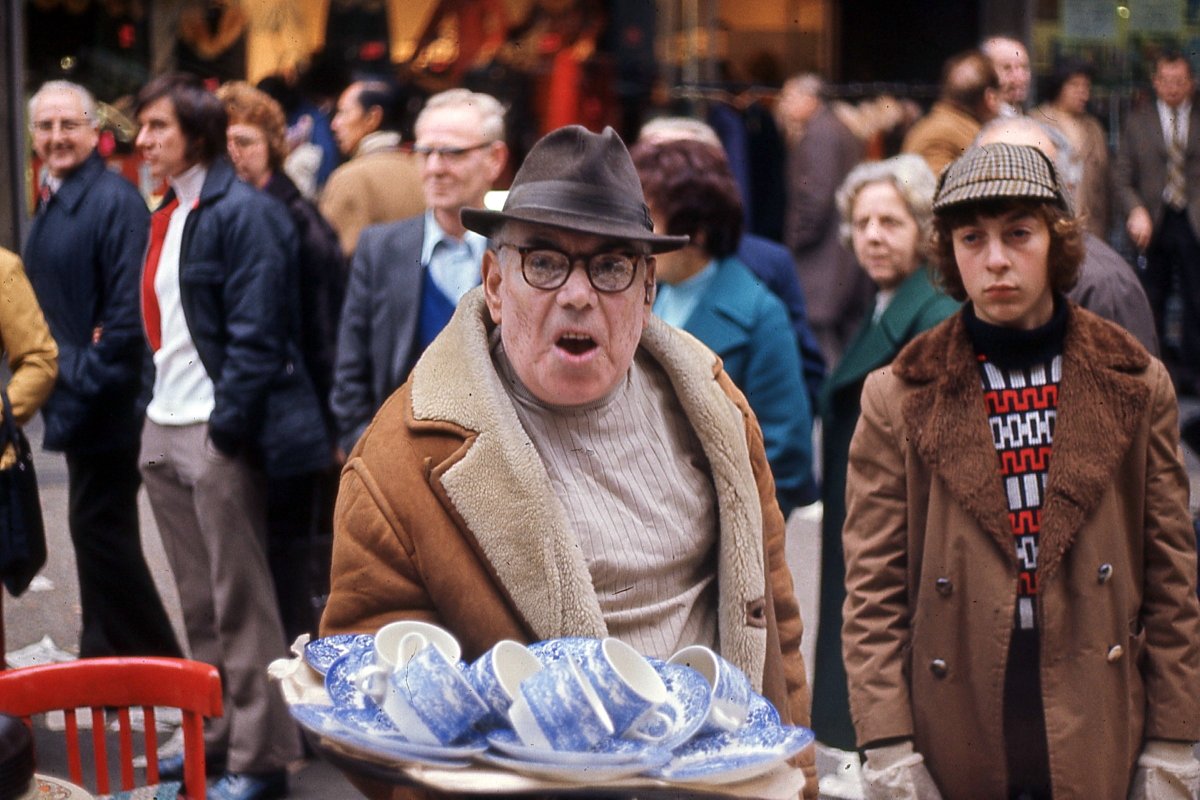 Crockery seller in Petticoat Lane and his disinterested assistant (c.1970), as photographed by Andrew Greener and published here for the first time.