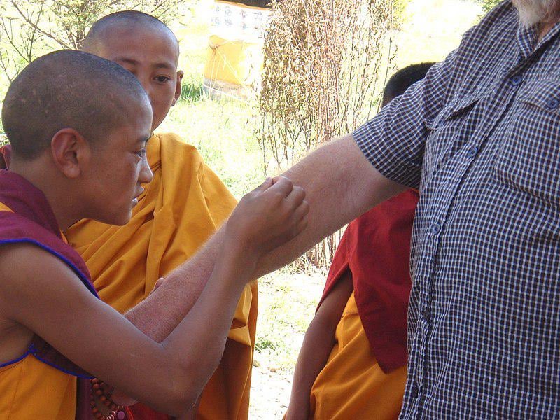 A Buddhist monk looking surprised that a white tourist have hairy arms.