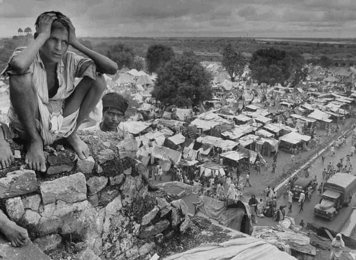 Boy sitting on rock ledge above refugee camp at Purana Qila in Delhi during the partition of India, 1947. Photograph by Margaret Bourke-White.
