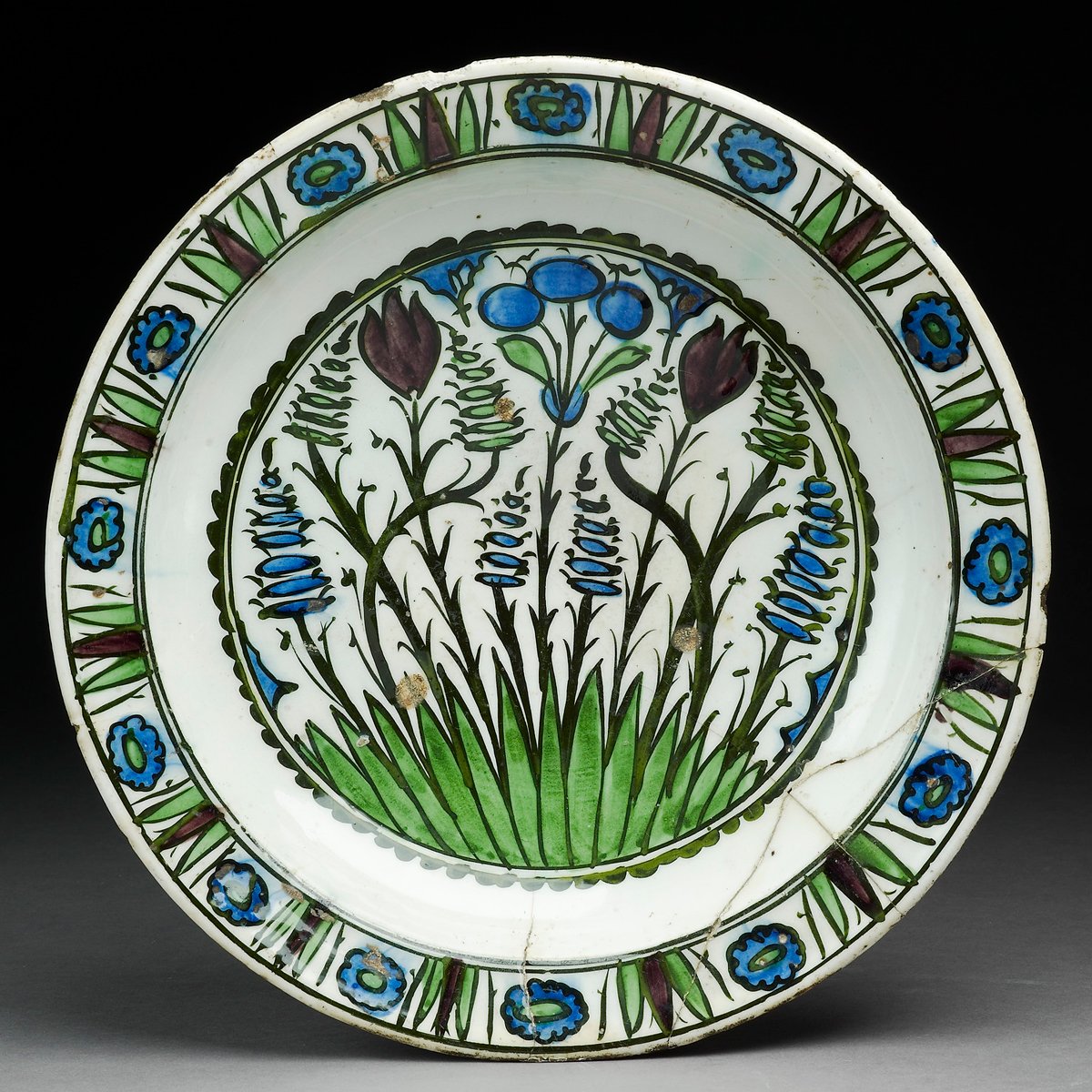 This 16th-century dish is a Syrian adaptation of the floral decoration typical of Iznik pottery. It is painted in black, green, blue and purple pigments under a colourless glaze and features stylized tulips and hyacinths.⁠ ⁠ You will find it on display in the Islamic Middle…