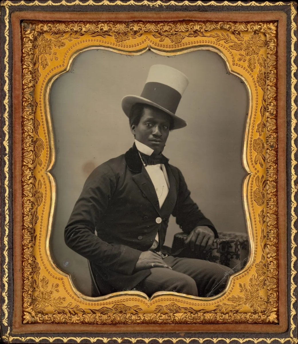 This is a circa 1855 daguerreotype of an unidentified African American gentleman. The glass plate is encased in a gilt and velvet-lined case, which was the most popular form of adorning and protecting these keepsakes. He wears a light-colored stovepipe hat tilted at a jaunty