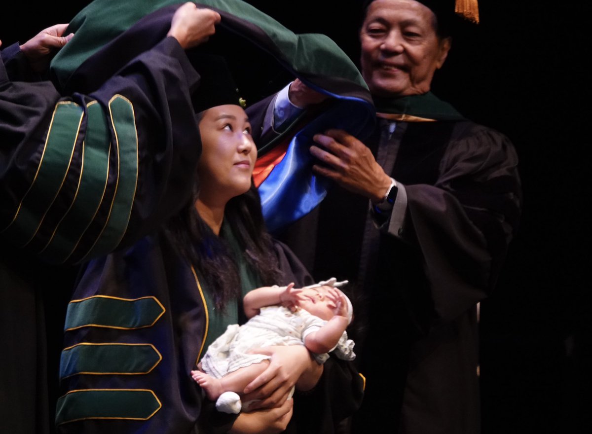 Dr. Amy Thien Du is hooded by her father Dr. Loc Du as she holds her daughter Emmie @FloridaAtlantic @CityBocaRaton @pbcgov @SunSentinel @FloridaMedical @AmerMedicalAssn