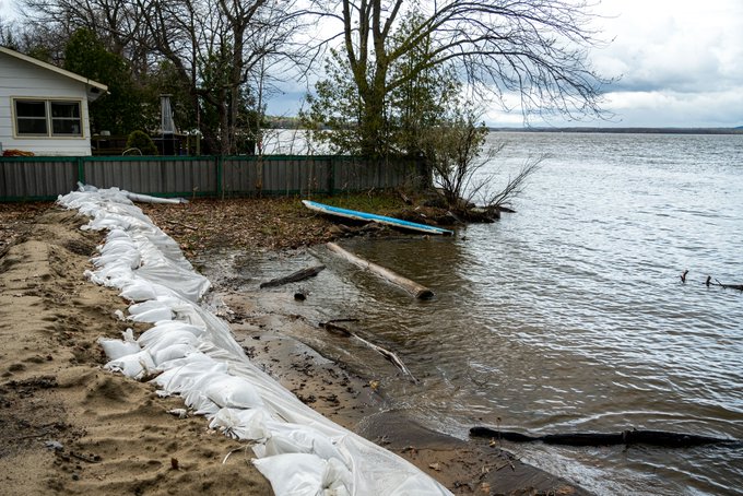 House with sandbags near higher waters at the river's edge.